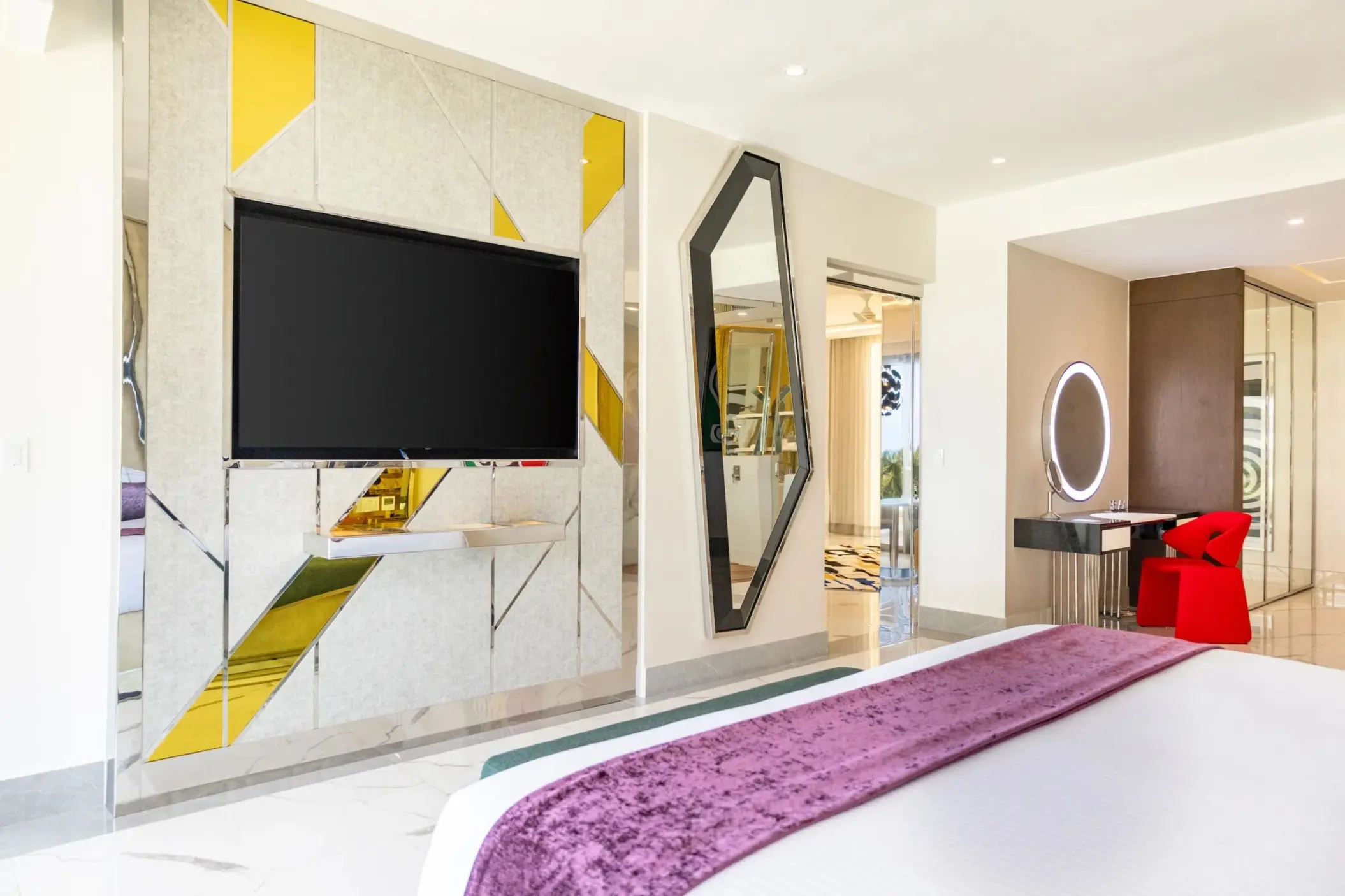 Two-bedroom suite with a geometric gold-accented wall and red velvet chair at Hotel Mousai Cancun, Cancun