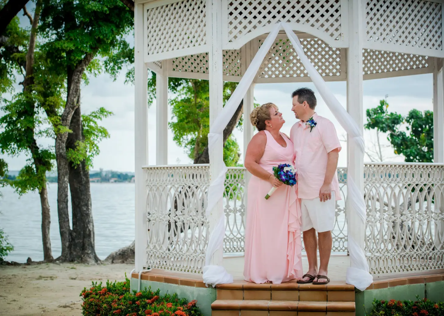 The bride and groom standing in a white lattice beach gazebo at Riu Negril, Negril