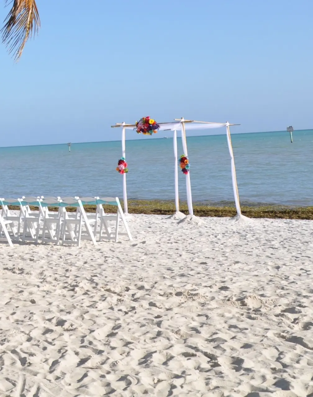 Beachfront wedding ceremony setup with white chairs and floral arch at Riu Negril, Jamaica