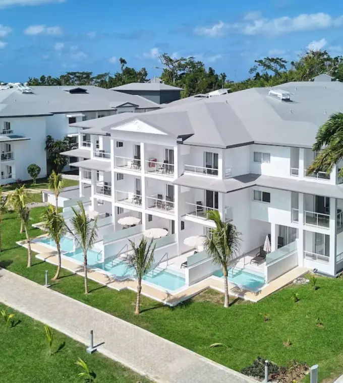 White suite buildings with private swim-up pools and tropical gardens at Riu Negril