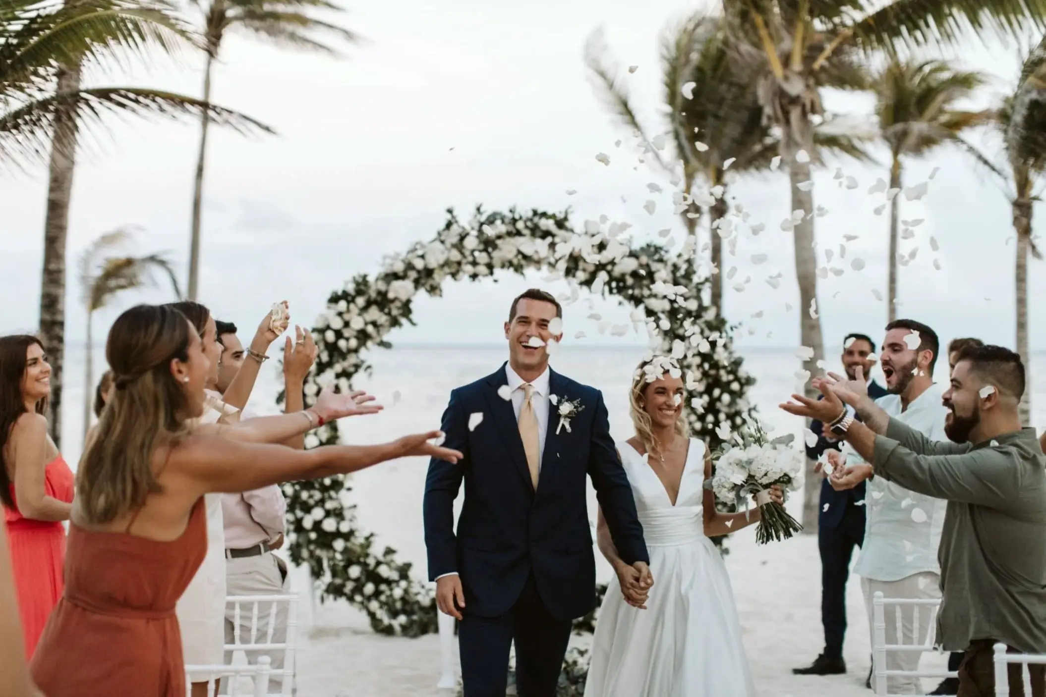 Wedding guests tossing petals at a couple after their beach ceremony at Riu Negril, Jamaica