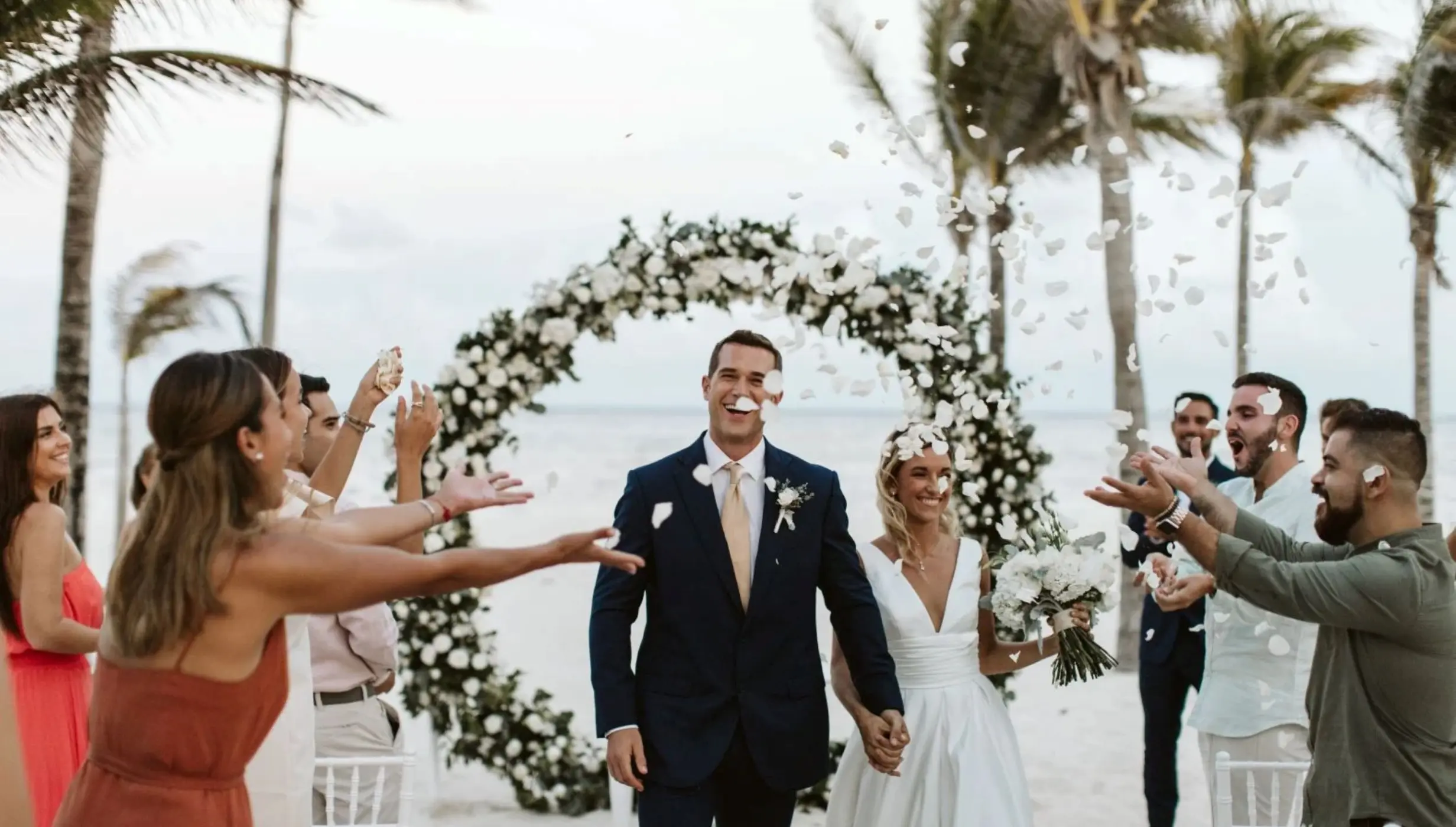 Wedding guests tossing petals at a couple after their beach ceremony at Riu Negril, Jamaica