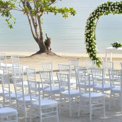 Beachfront wedding ceremony with white chairs and floral arch at Riu Palace Aquarelle, Montego Bay