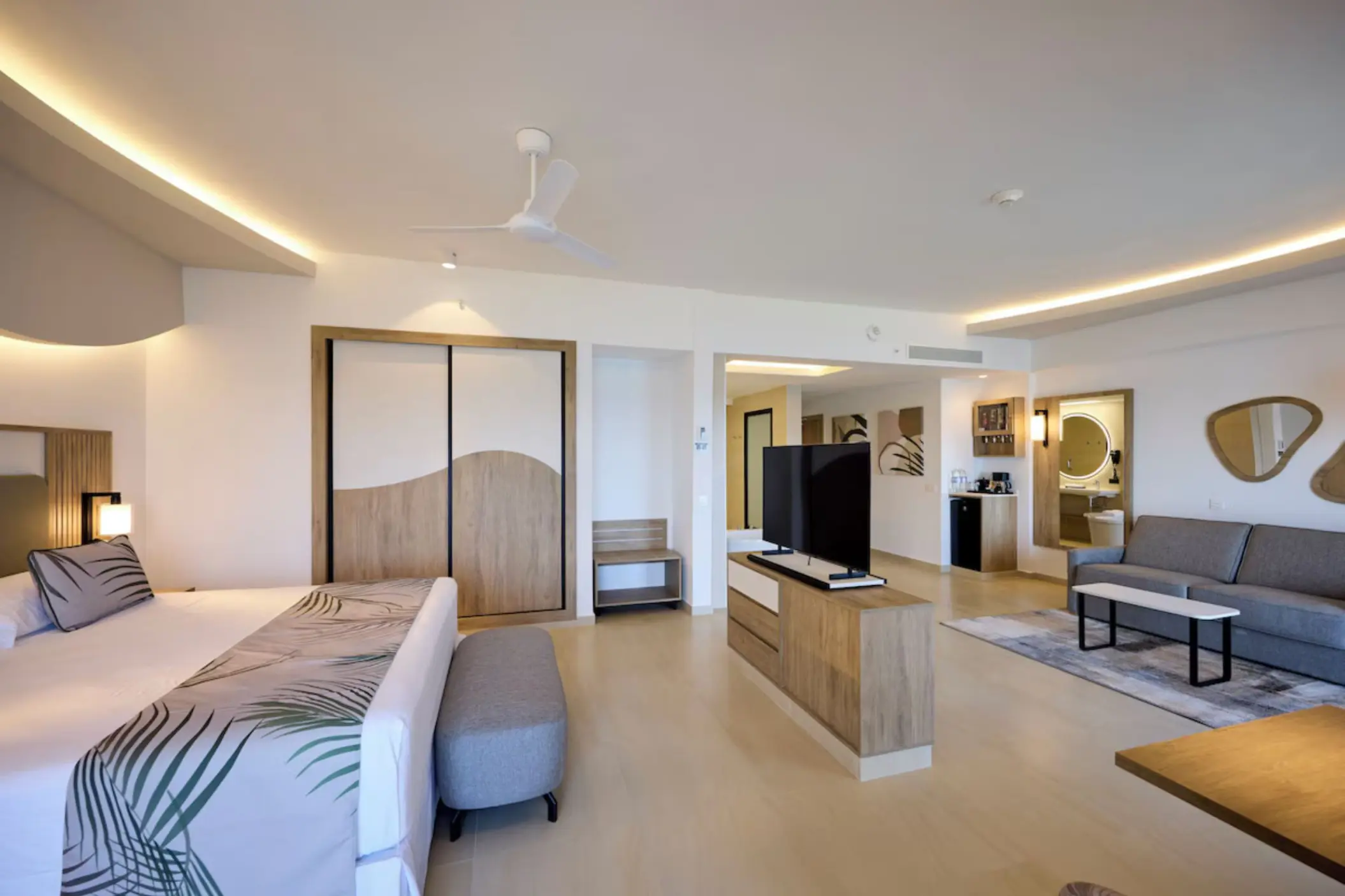 Modern suite with bed, lounge area, and wood accents at Riu Palace Aquarelle, Montego Bay
