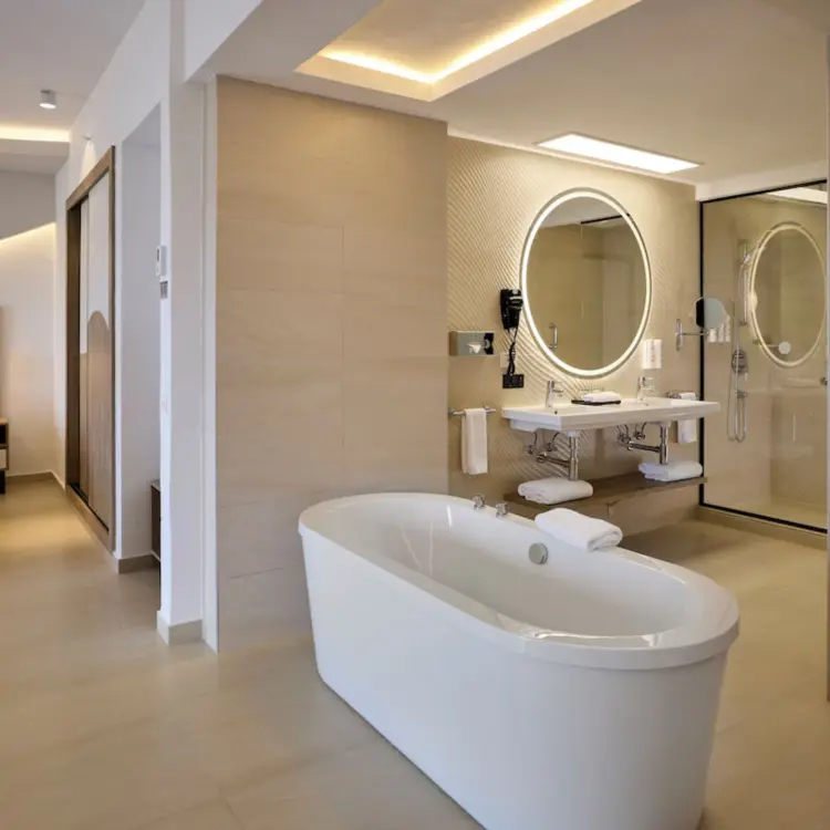 Modern suite with a freestanding bathtub, vanity, and bedroom area at Riu Palace Aquarelle, Montego Bay