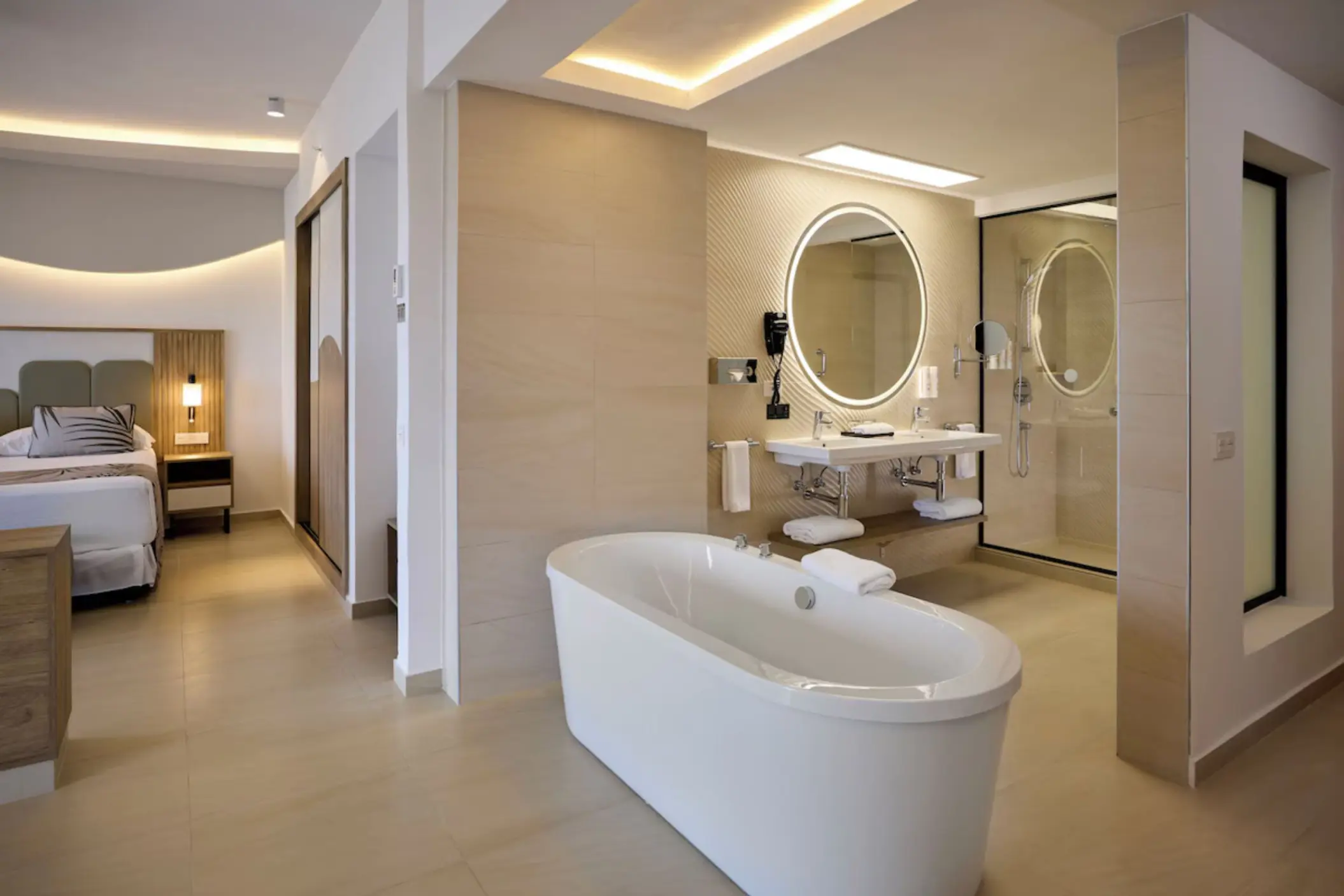 Modern suite with a freestanding bathtub, vanity, and bedroom area at Riu Palace Aquarelle, Montego Bay