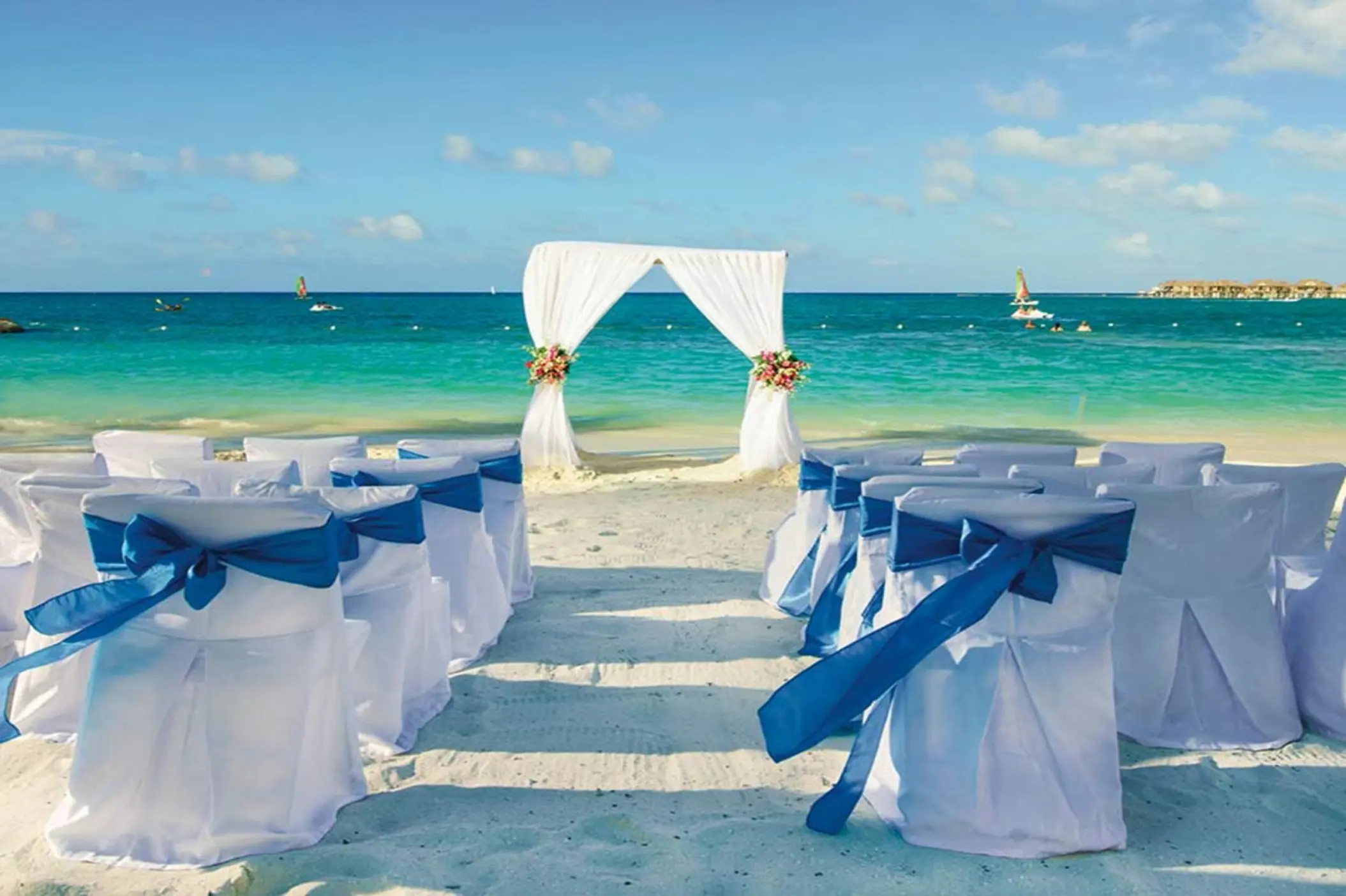 Beachfront wedding ceremony with white arch and blue ribbons at Riu Reggae, Montego Bay
