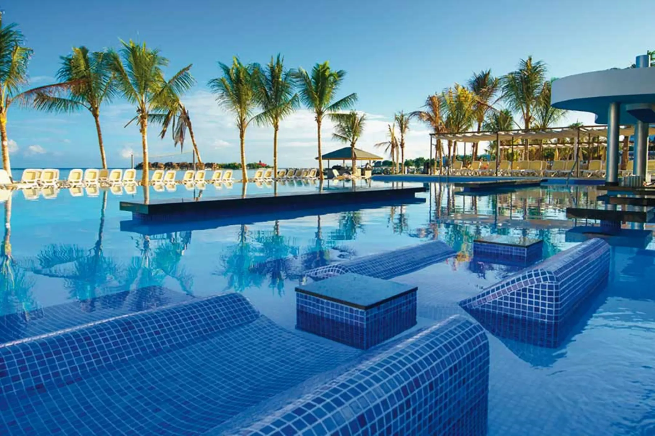 Hotel Riu Reggae infinity pool with submerged tile loungers and palm trees, Montego Bay