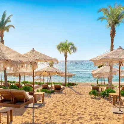 Beach club with thatched umbrellas and lounge chairs at Hyatt Vivid Grand Island, Cancun