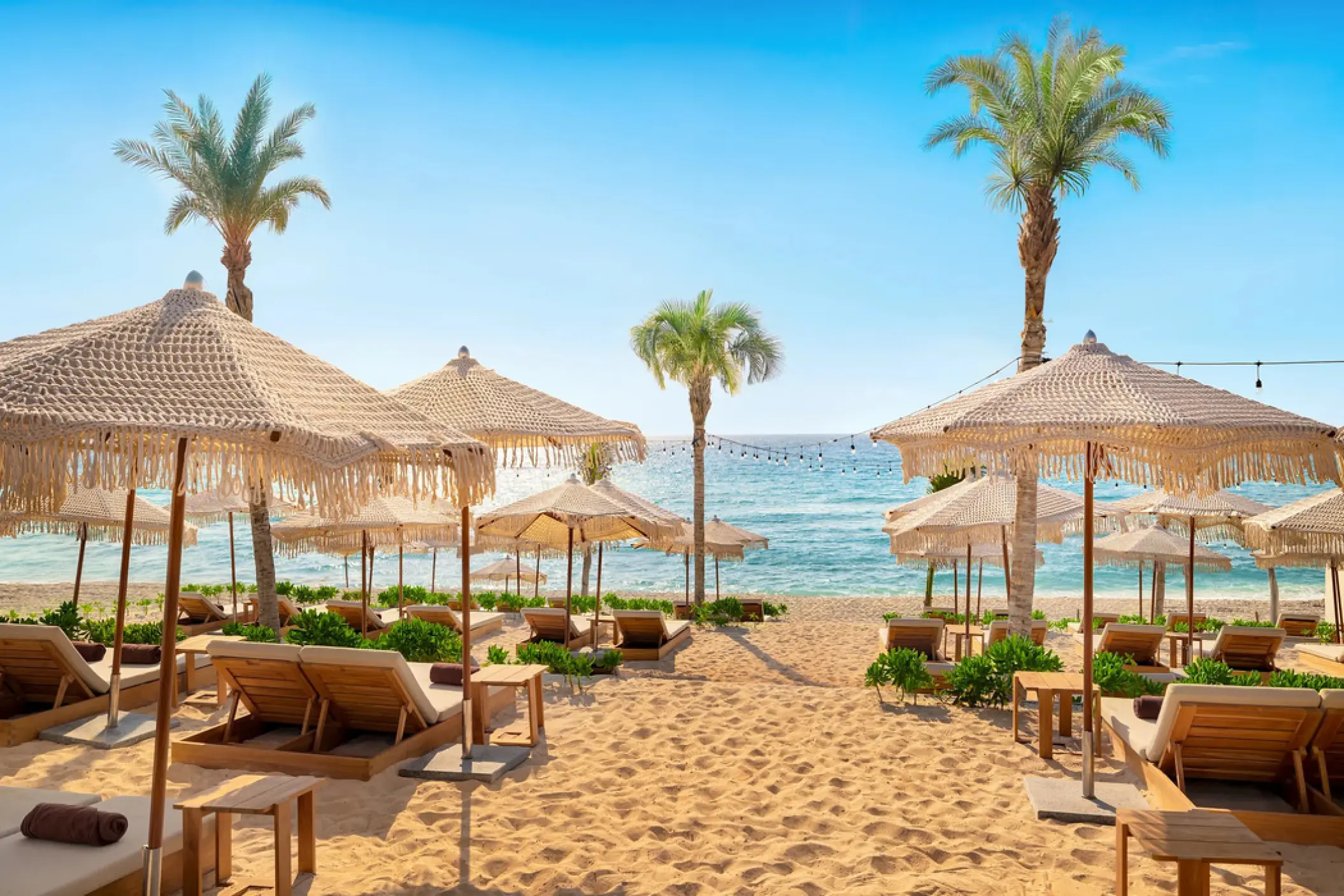 Beach club with thatched umbrellas and lounge chairs at Hyatt Vivid Grand Island, Cancun
