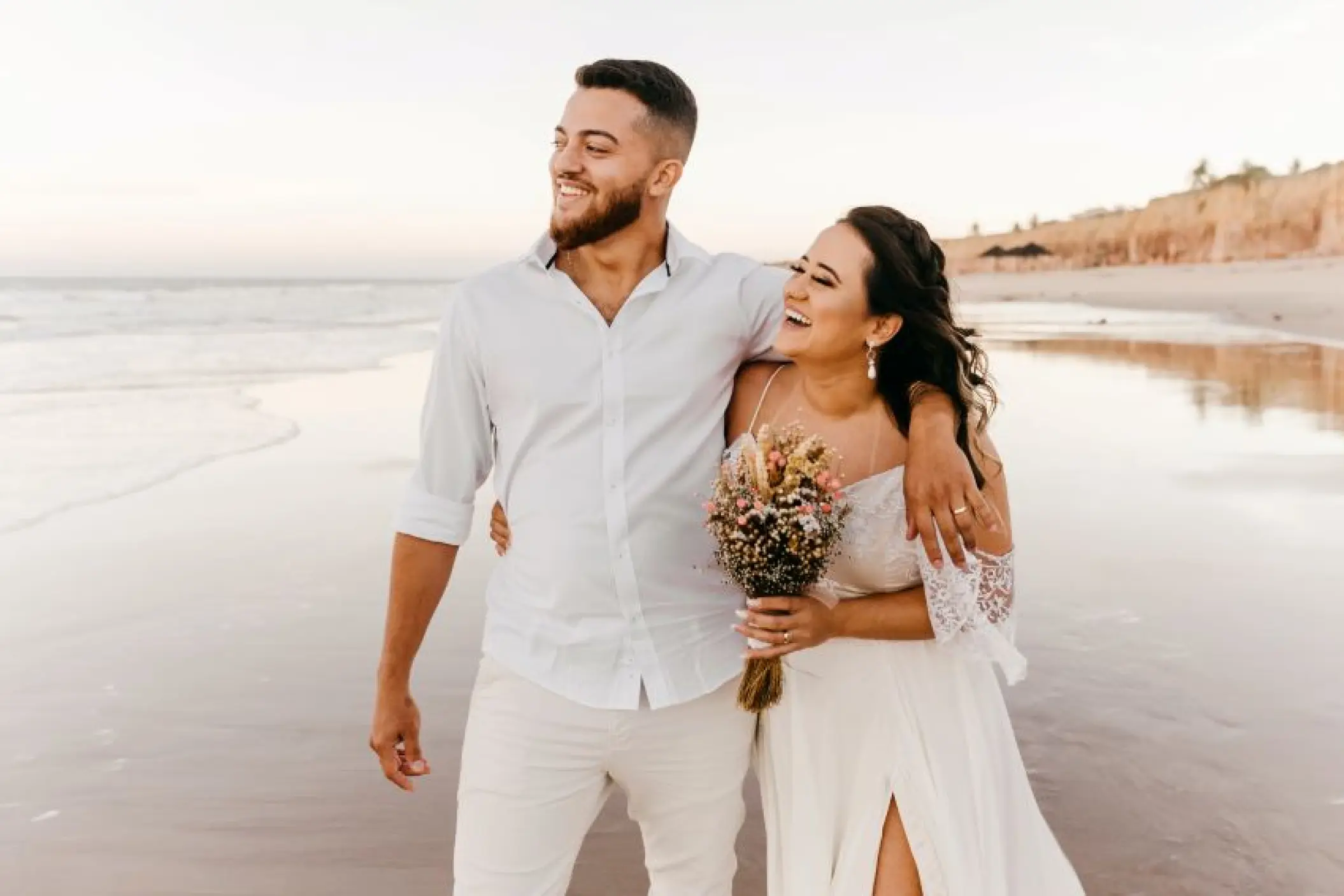 Laughing bride and groom walking on the beach at Hyatt Vivid Grand Island, Cancun