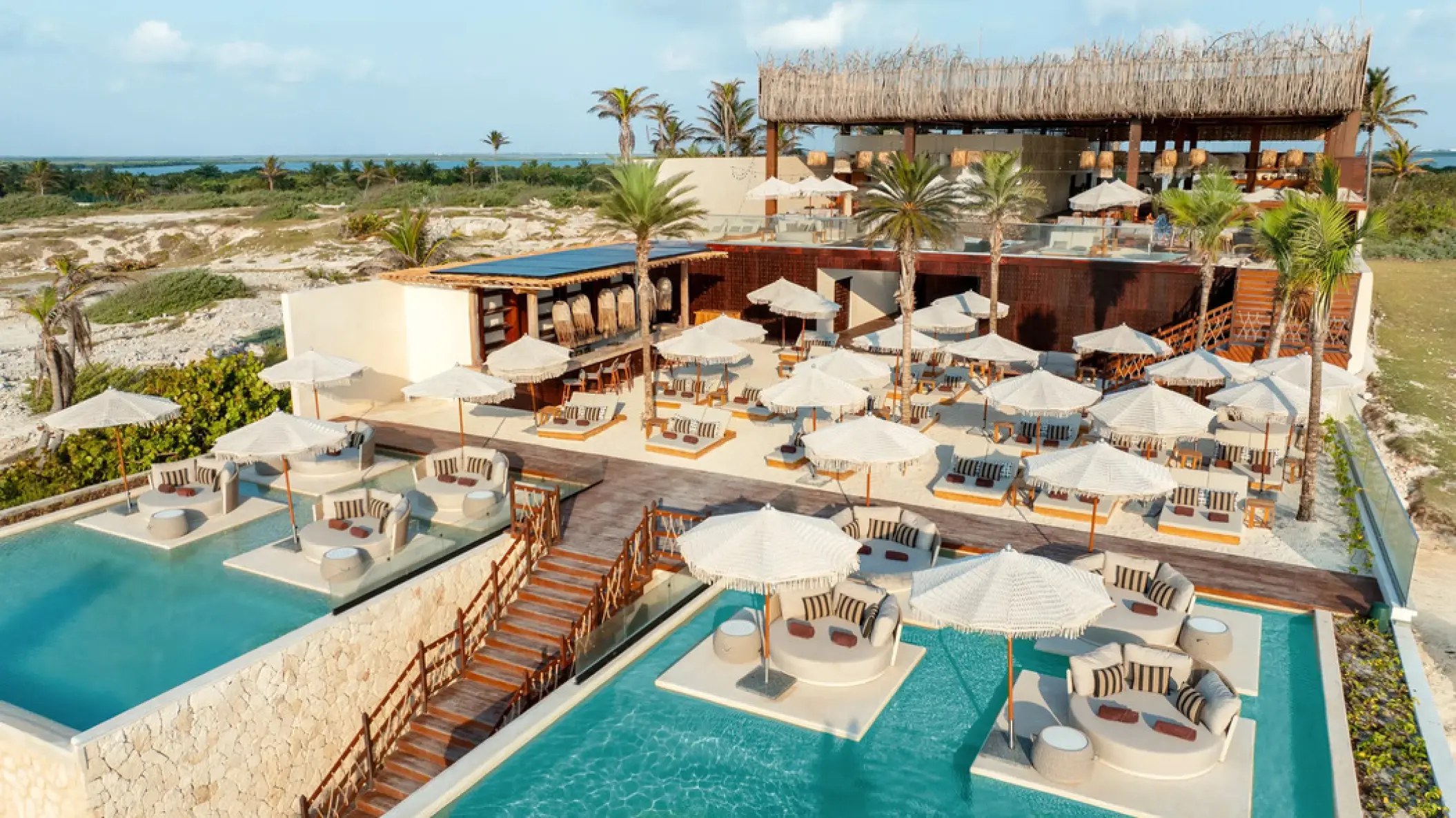 Ennea Beach Club wedding reception venue with lounge pools and umbrellas at Hyatt Vivid Grand Island, Cancun