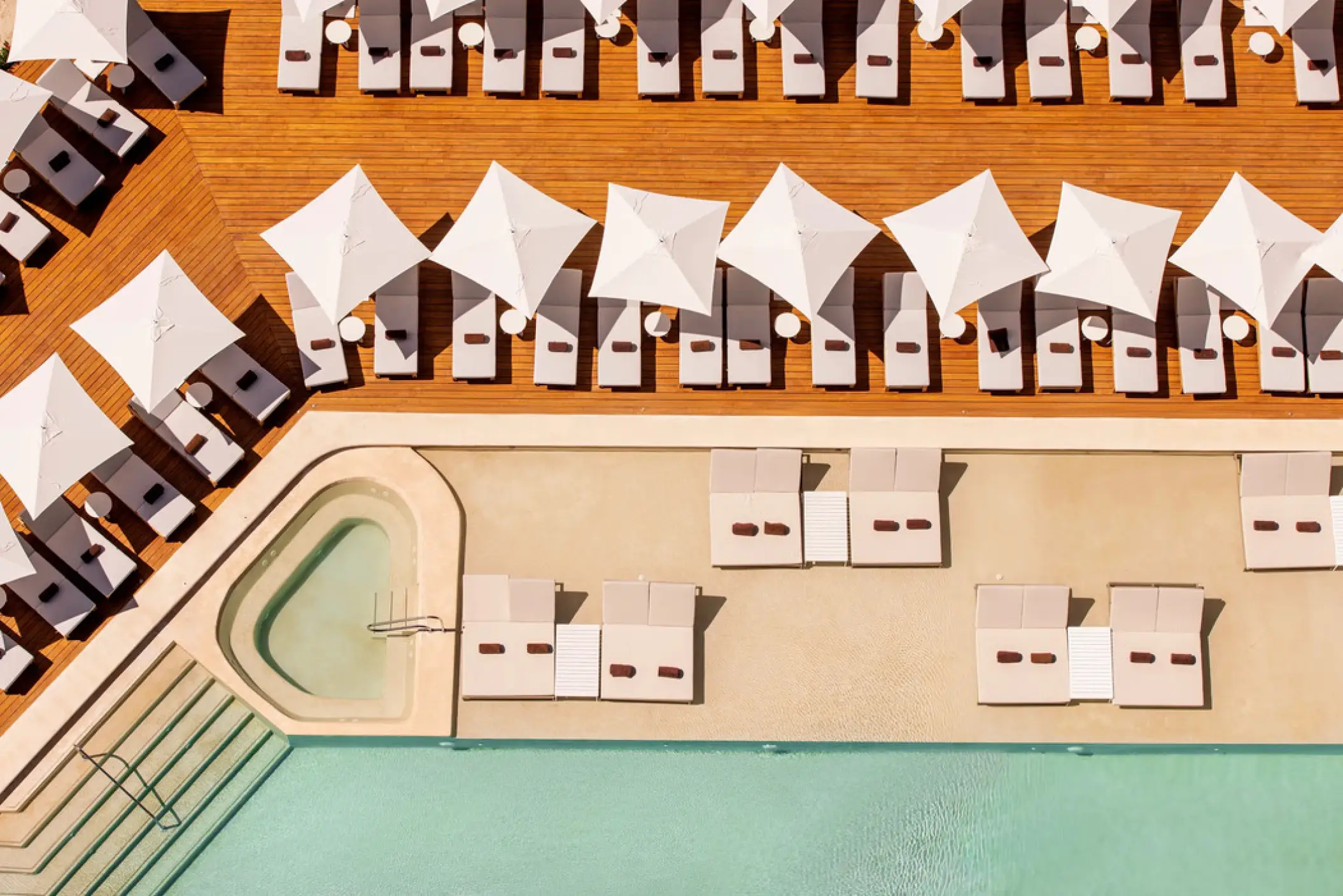 Aerial view of orderly rows of sun loungers and umbrellas on the pool deck at Hyatt Vivid Grand Island, Cancun