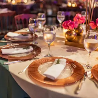 Wedding reception table setup with gold plates and pink roses at Hyatt Vivid Grand Island, Cancun