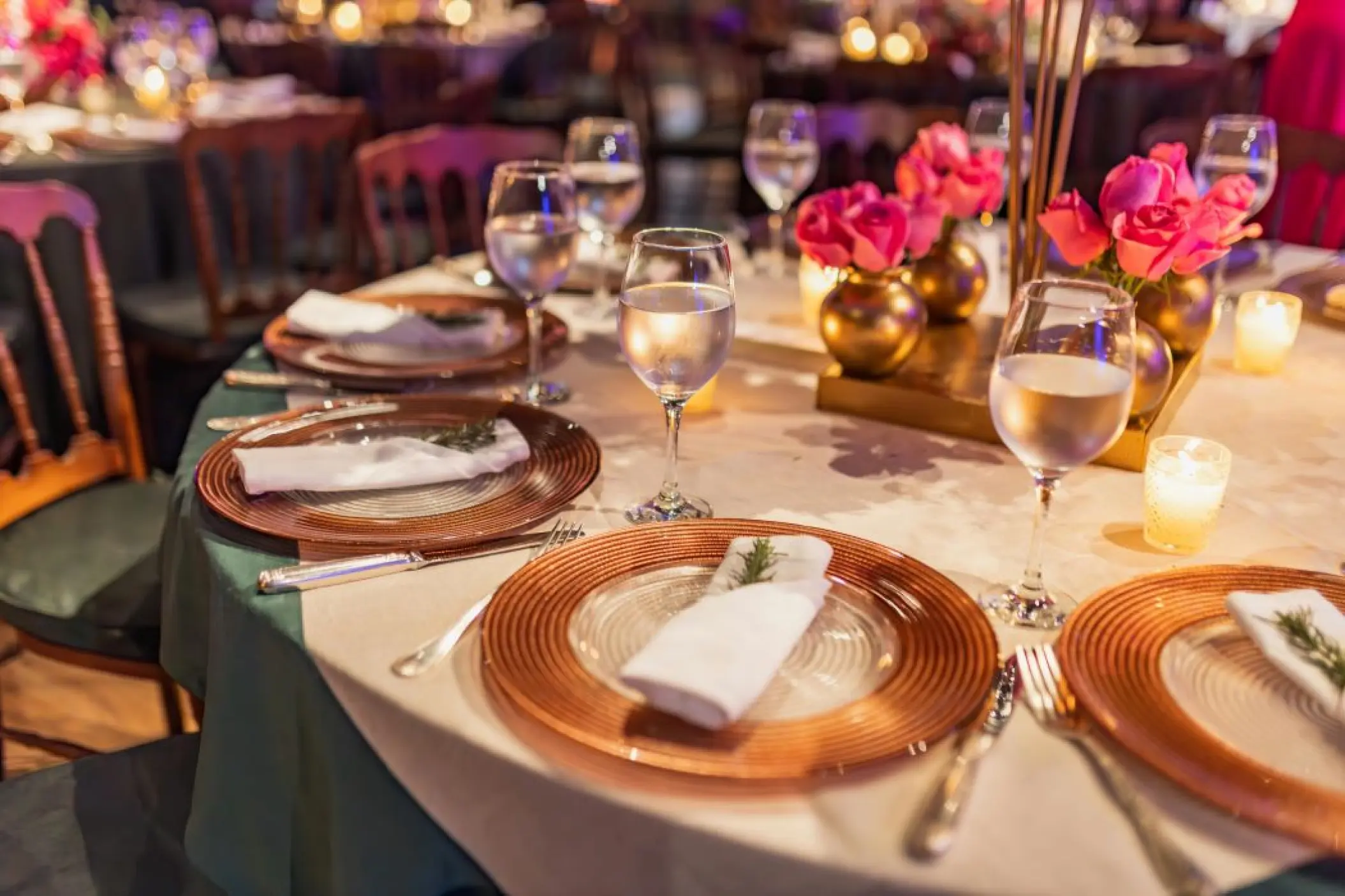 Wedding reception table setup with gold plates and pink roses at Hyatt Vivid Grand Island, Cancun