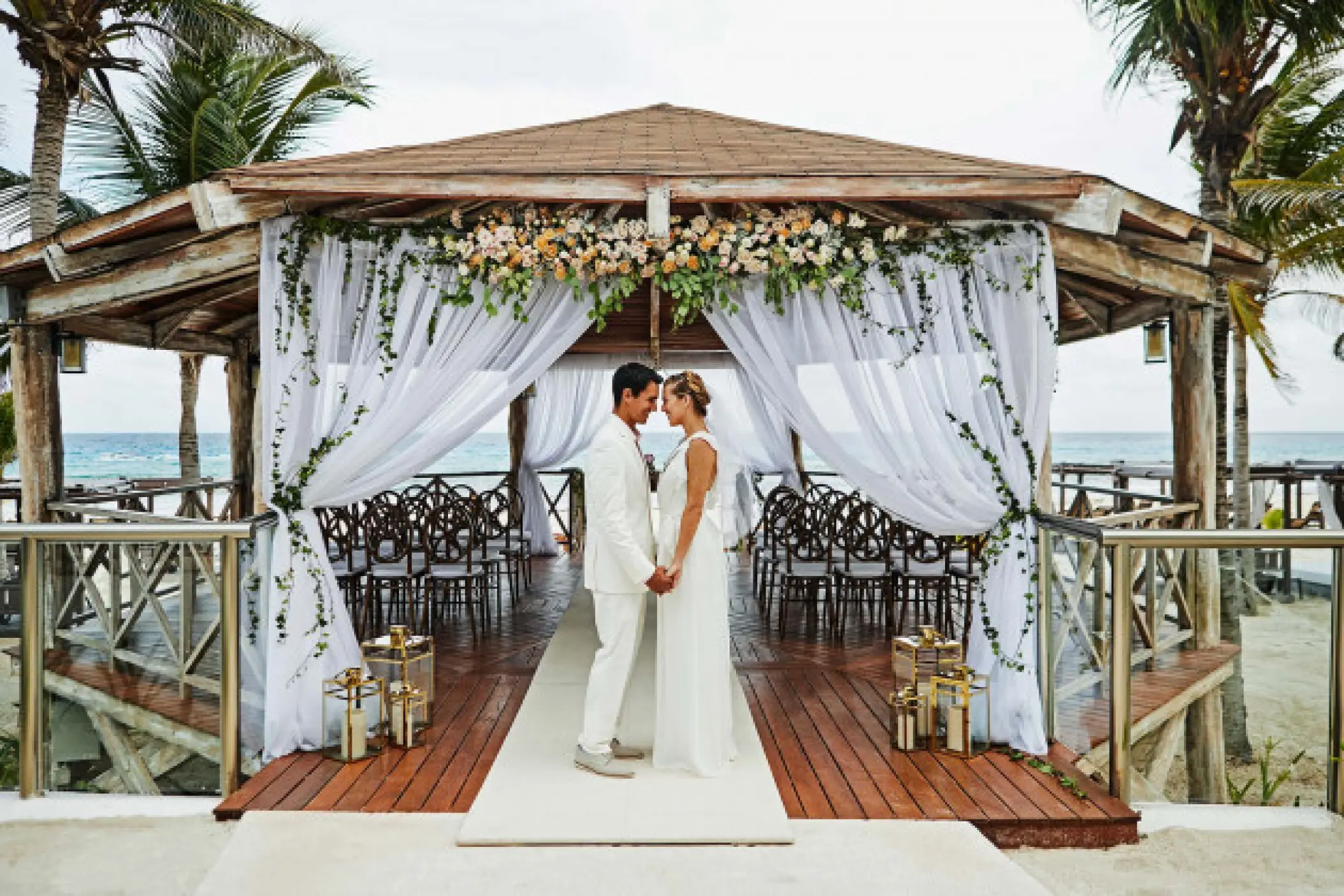 The couple holding hands under a decorated wooden wedding gazebo at Hyatt Zilara Cancun