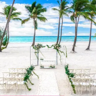 Beachfront wedding ceremony with white chairs and floral arch at Hyatt Zilara Cap Cana, Punta Cana