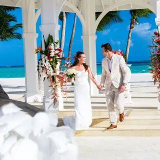 Bride and groom walking out of the beach gazebo at Hyatt Zilara Cap Cana, Punta Cana