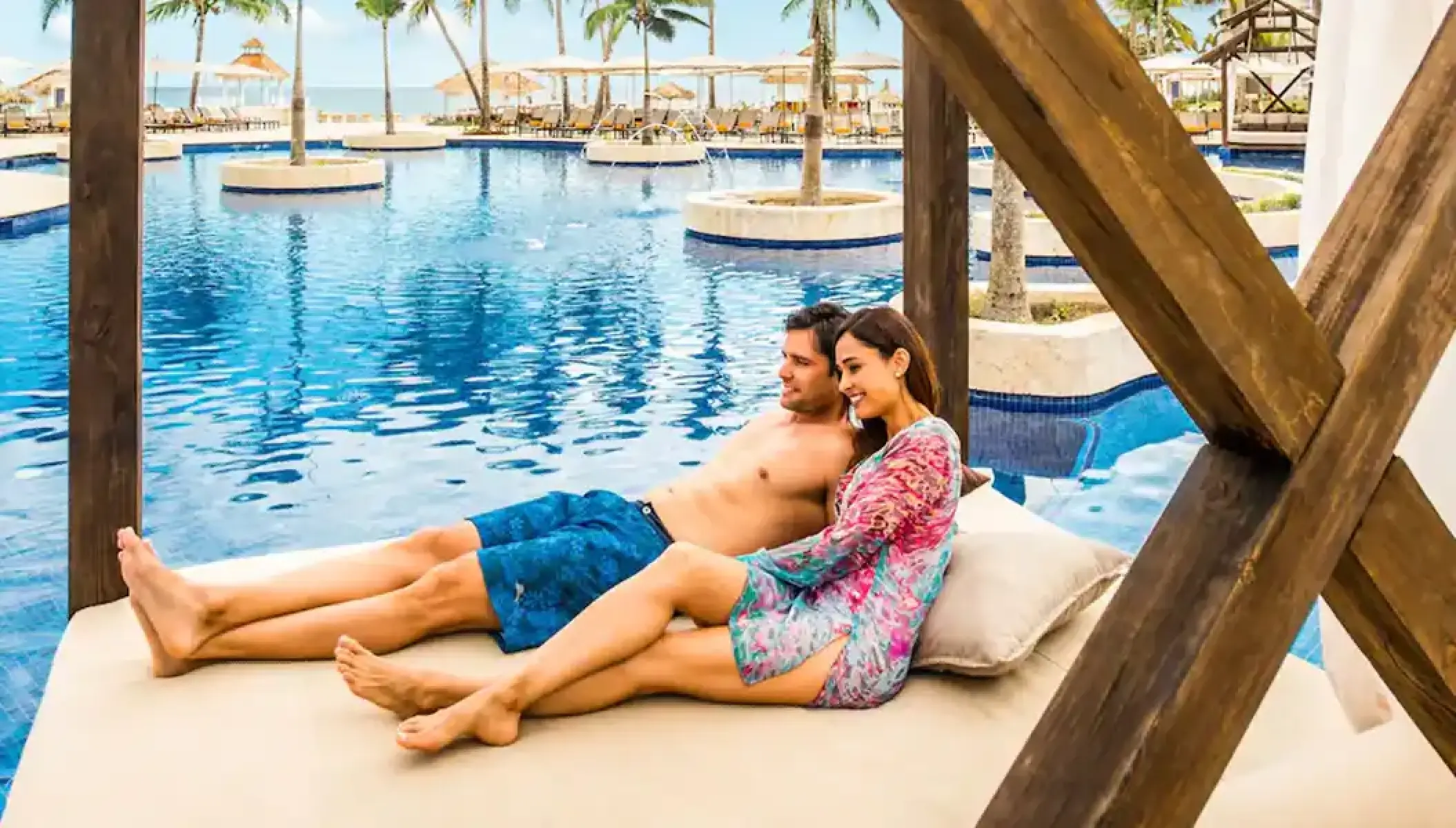 A couple relaxing on a poolside daybed at Hyatt Zilara Rose Hall, Montego Bay