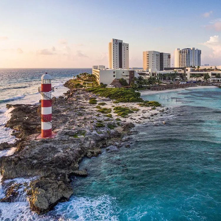 Red and white striped lighthouse on the rocky coastline of Hyatt Ziva Cancun, Cancun
