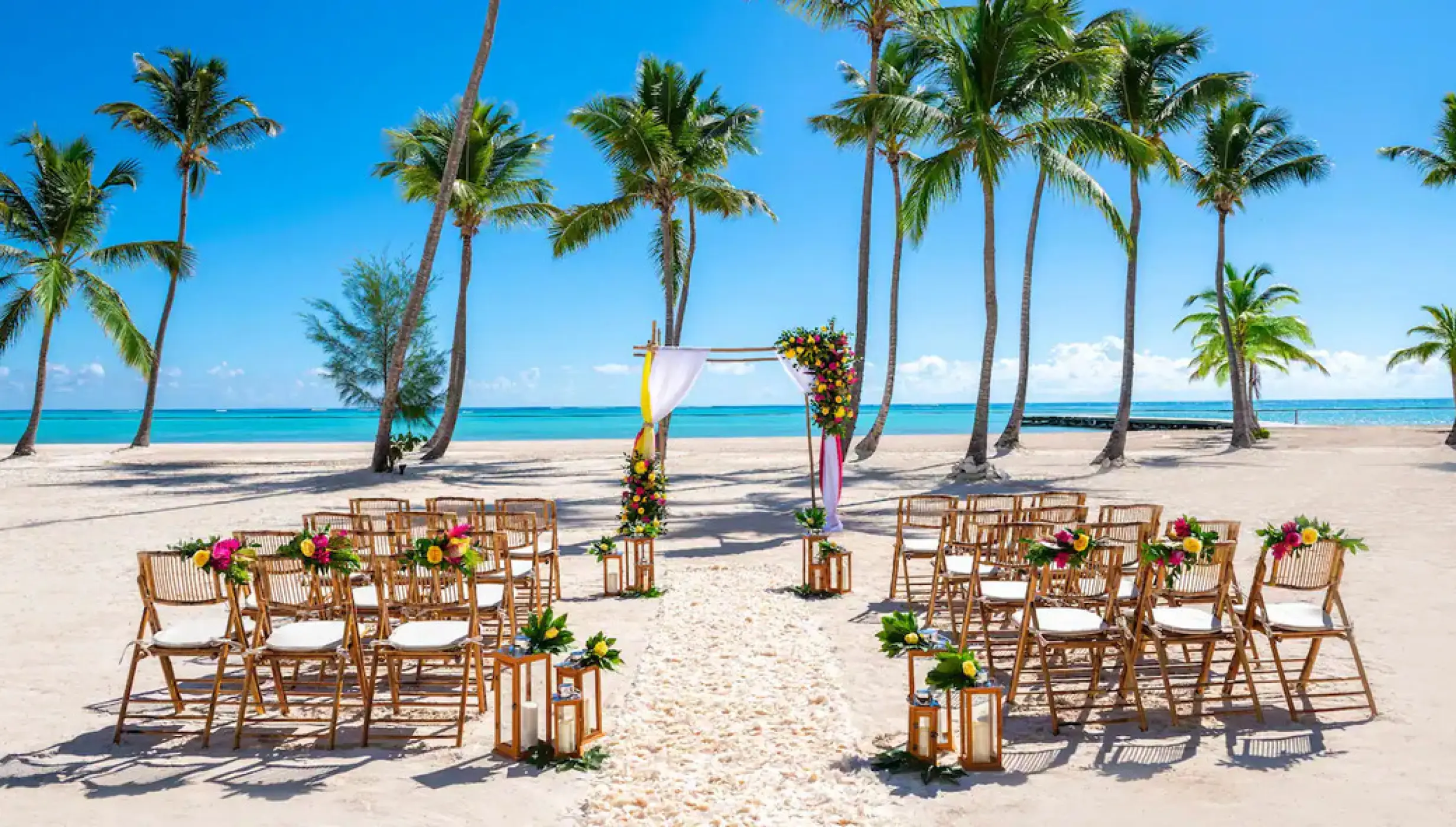 Beachfront wedding ceremony setup with an arch and wooden chairs at Hyatt Ziva Cap Cana, Punta Cana