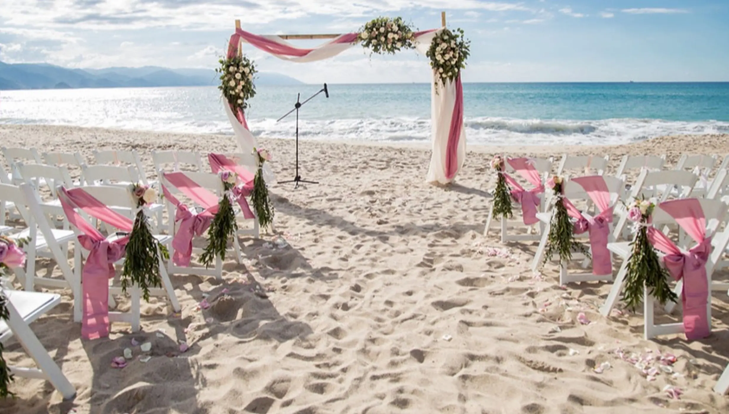Beachfront wedding ceremony setup with pink sashes at Hyatt Ziva Puerto Vallarta