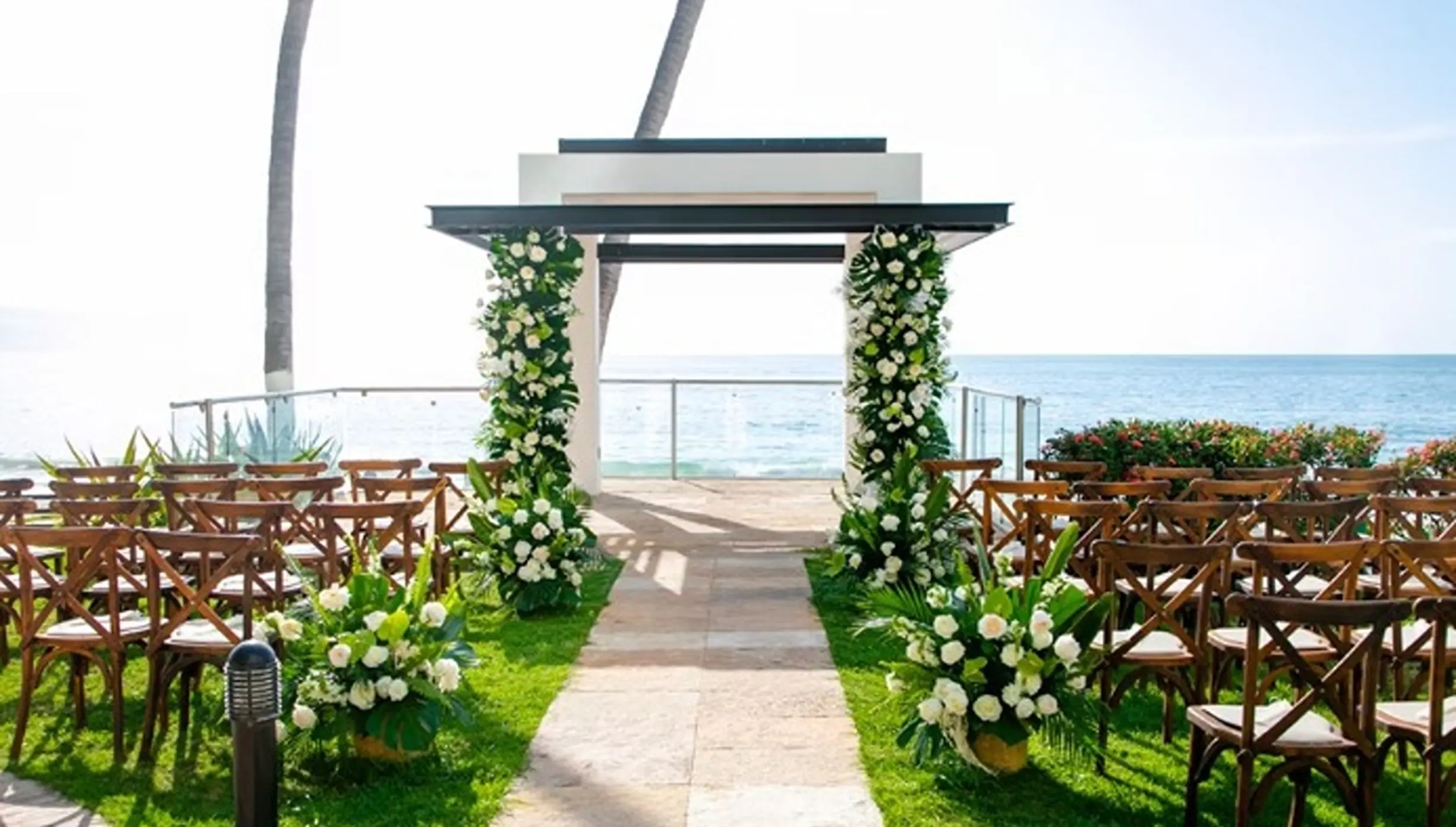 Oceanfront wedding ceremony at Hyatt Ziva Puerto Vallarta with a floral-draped gazebo and wooden cross-back chairs