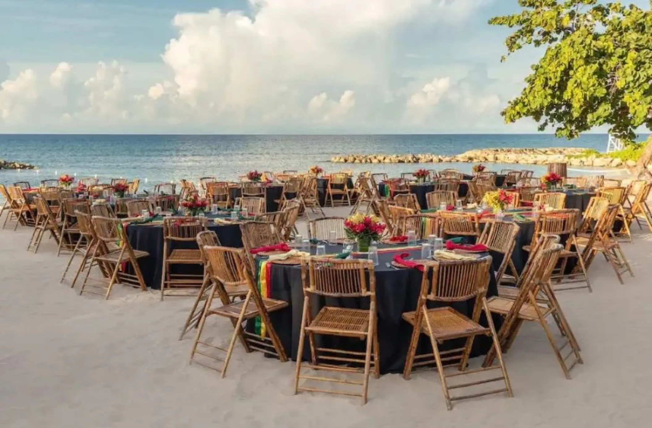 Beachfront wedding reception with bamboo chairs and dark linens at Hyatt Ziva Rose Hall, Montego Bay