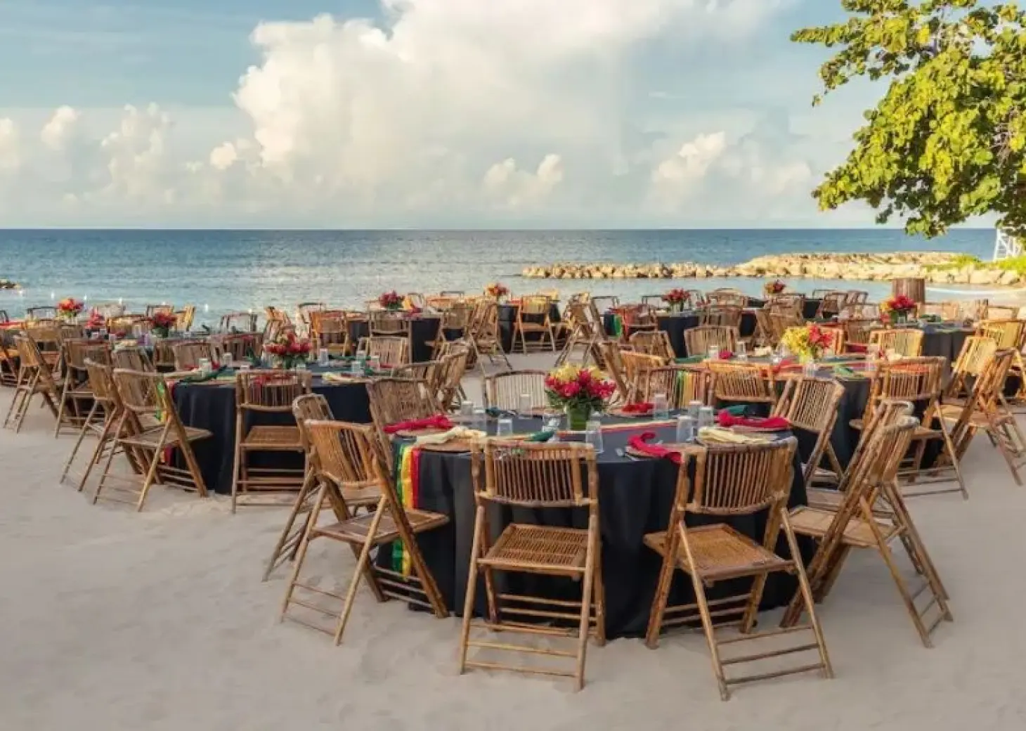 Beachfront wedding reception with bamboo chairs and dark linens at Hyatt Ziva Rose Hall, Montego Bay