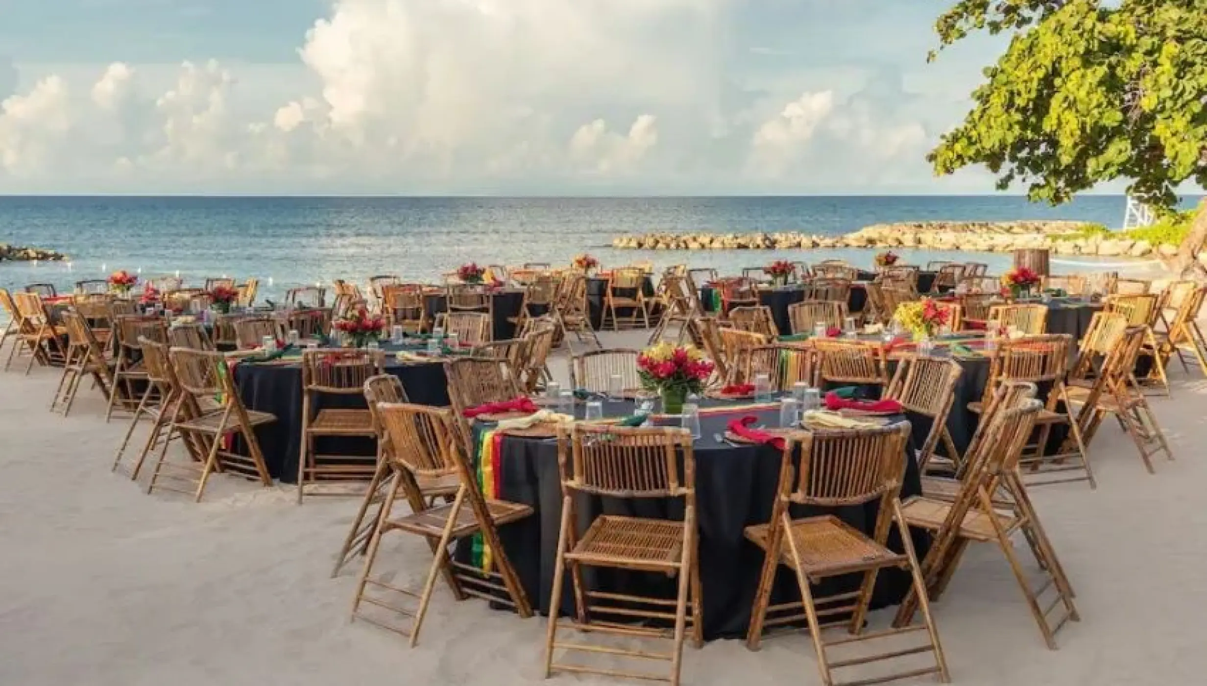 Beachfront wedding reception with bamboo chairs and dark linens at Hyatt Ziva Rose Hall, Montego Bay