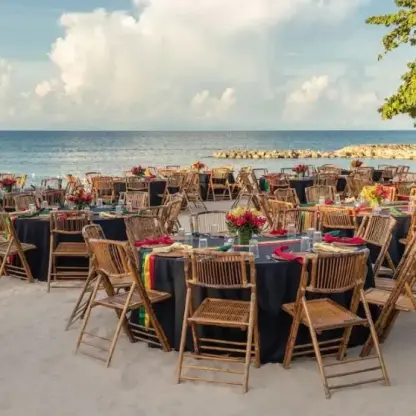 Beachfront wedding reception with bamboo chairs and dark linens at Hyatt Ziva Rose Hall, Montego Bay
