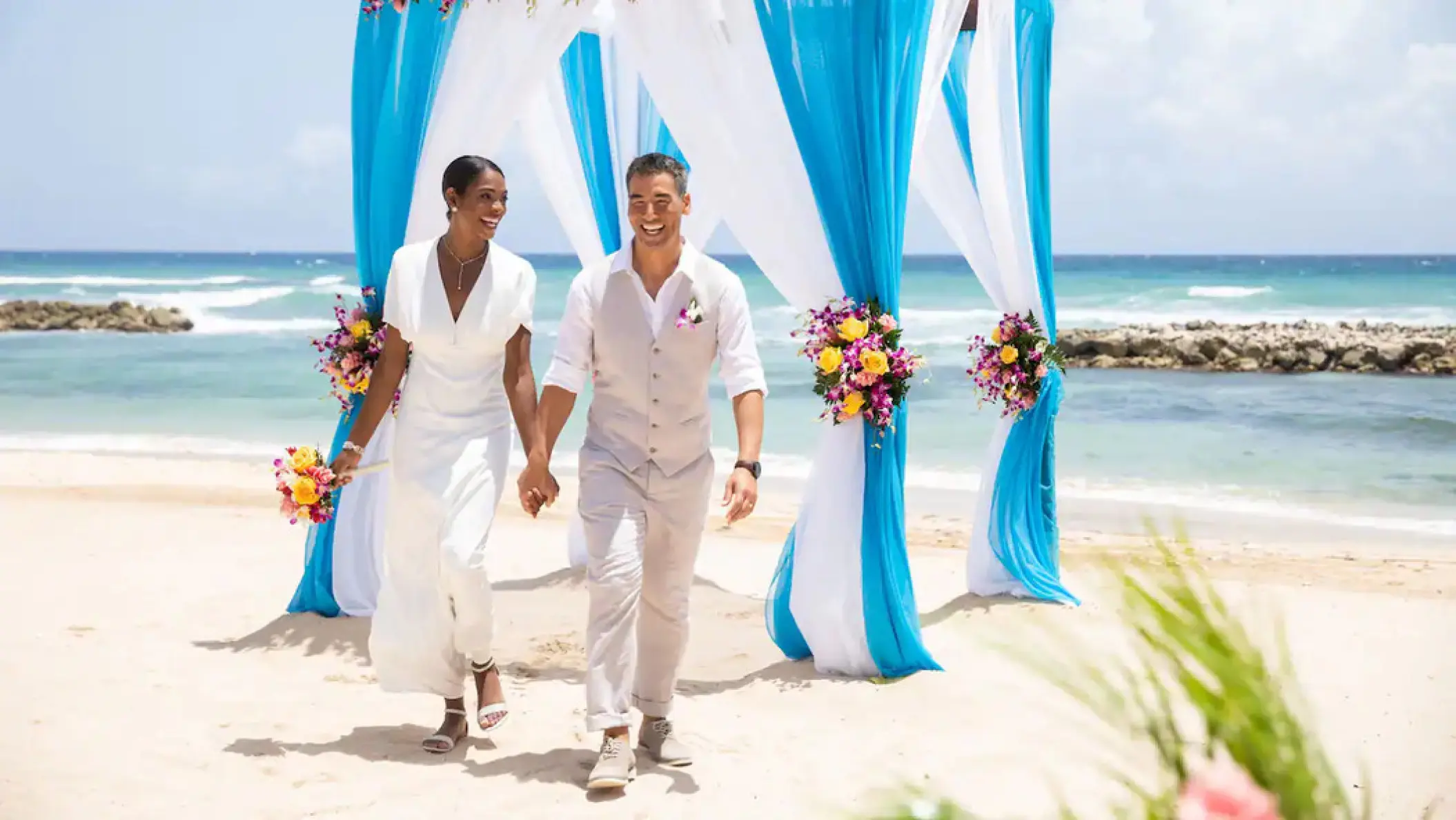 Bride and groom walking from a beach ceremony at Hyatt Ziva Rose Hall, Montego Bay