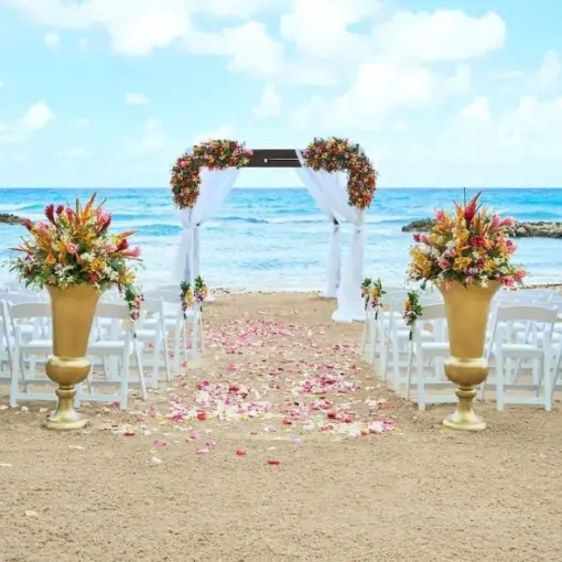 Beachfront wedding ceremony with white chairs and floral arch at Hyatt Ziva Rose Hall, Montego Bay