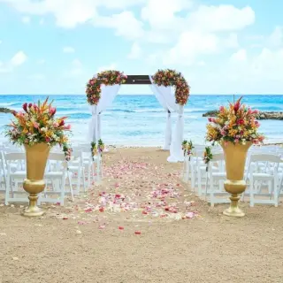 Beachfront wedding ceremony with white chairs and floral arch at Hyatt Ziva Rose Hall, Montego Bay