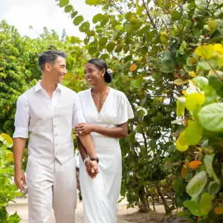 Bride and groom walking together through tropical greenery at Hyatt Ziva Rose Hall, Montego Bay