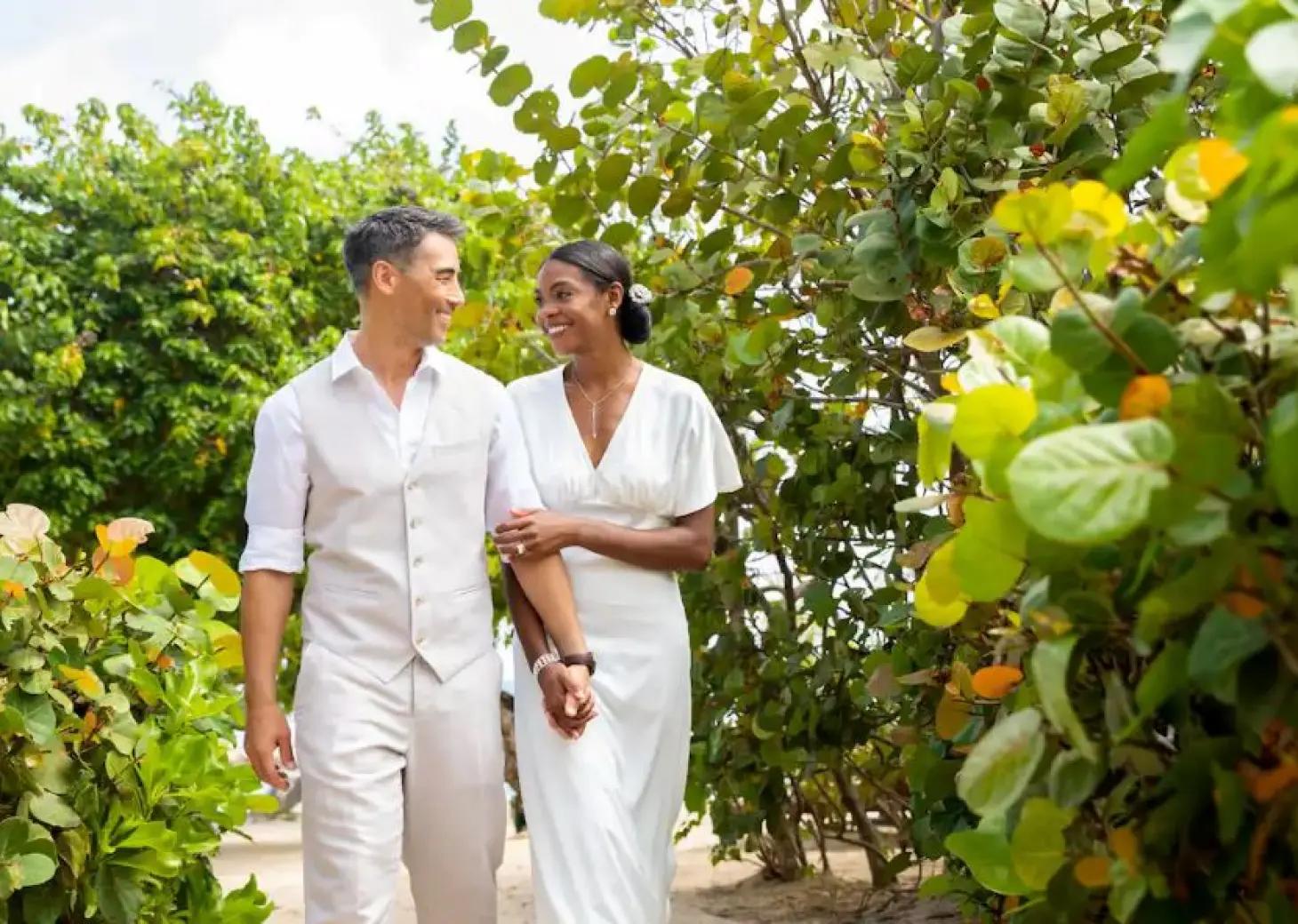 Bride and groom walking together through tropical greenery at Hyatt Ziva Rose Hall, Montego Bay