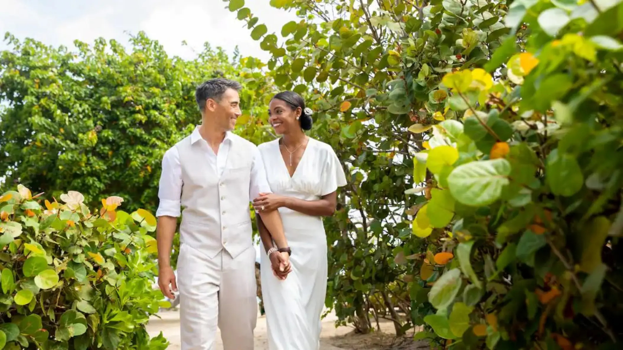 Bride and groom walking together through tropical greenery at Hyatt Ziva Rose Hall, Montego Bay