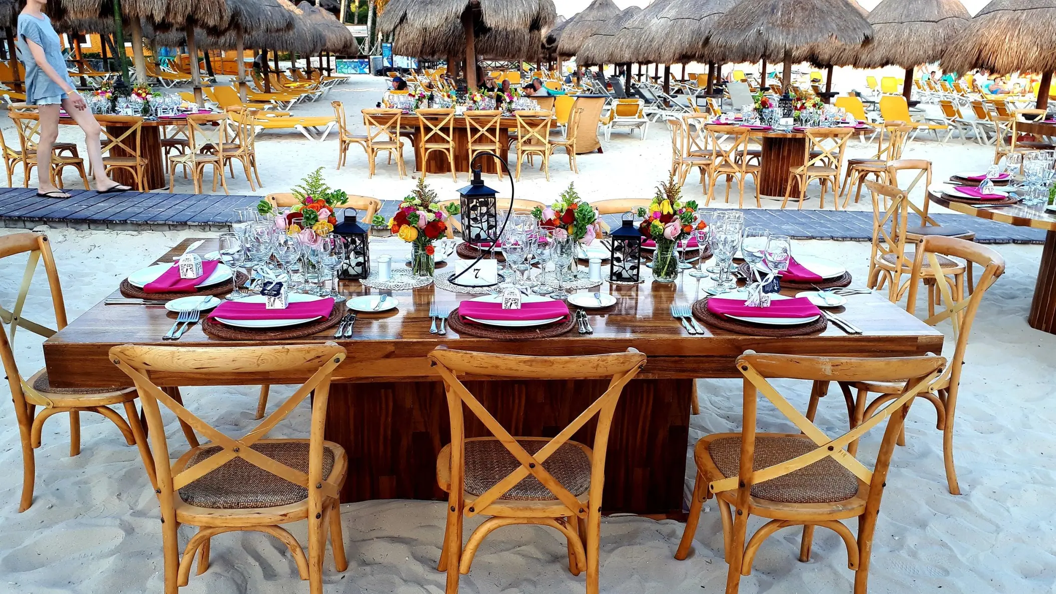 Beach wedding reception setup with wooden tables and pink napkins at Iberostar Quetzal, Playa Del Carmen