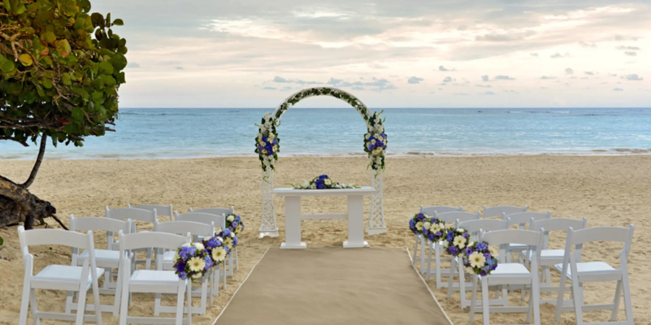 Beachfront wedding ceremony with a floral arch and white chairs at Iberostar Selection Bavaro, Punta Cana