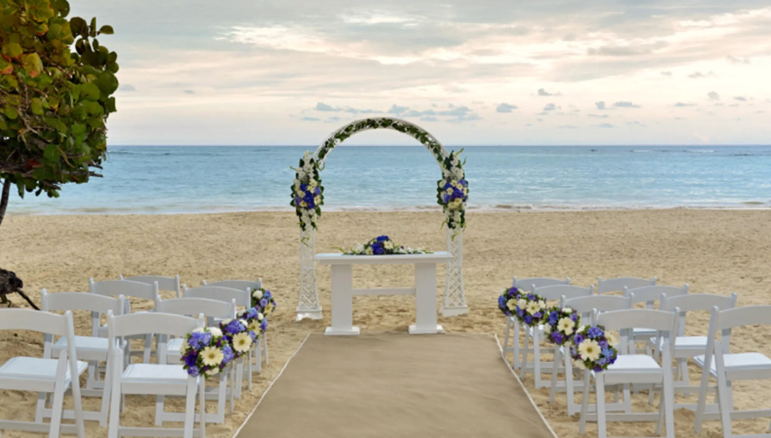 Beachfront wedding ceremony with a floral arch and white chairs at Iberostar Selection Bavaro, Punta Cana