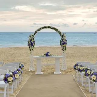 Beachfront wedding ceremony with a floral arch and white chairs at Iberostar Selection Bavaro, Punta Cana