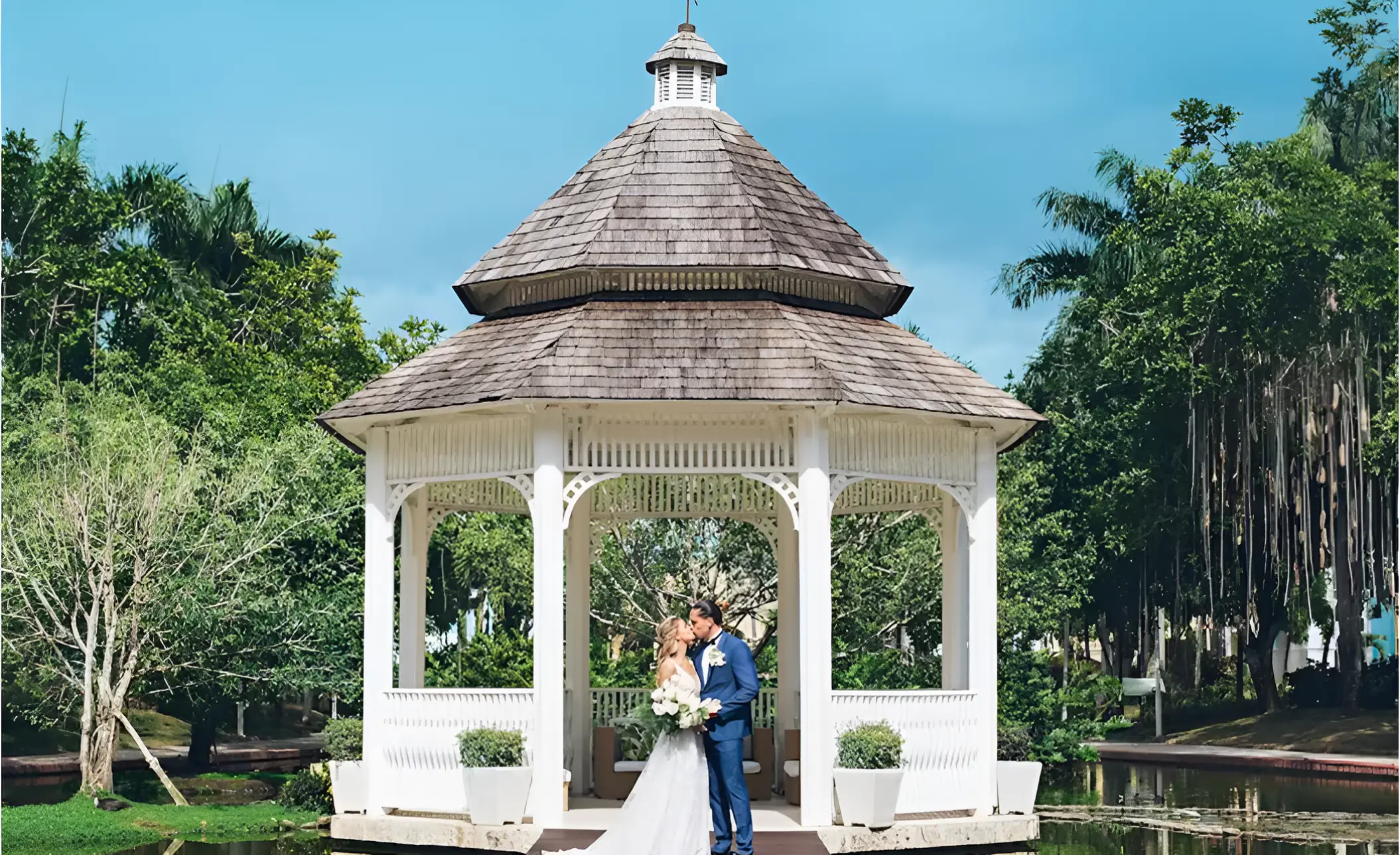 Bride and groom kissing under a white gazebo at Iberostar Hacienda Dominicus, La Romana