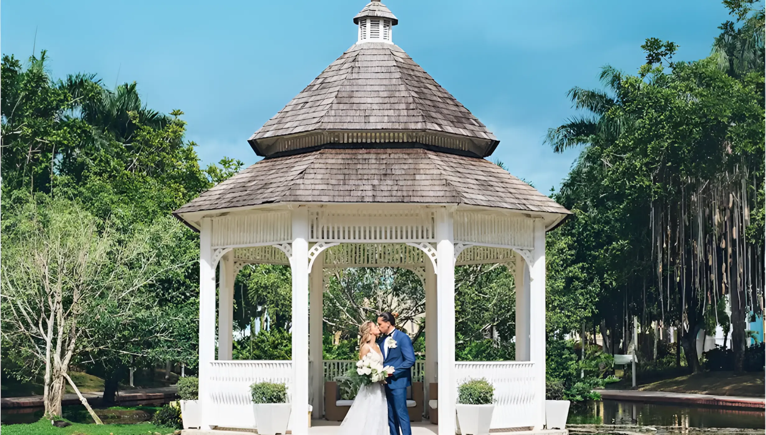 Bride and groom kissing under a white gazebo at Iberostar Hacienda Dominicus, La Romana