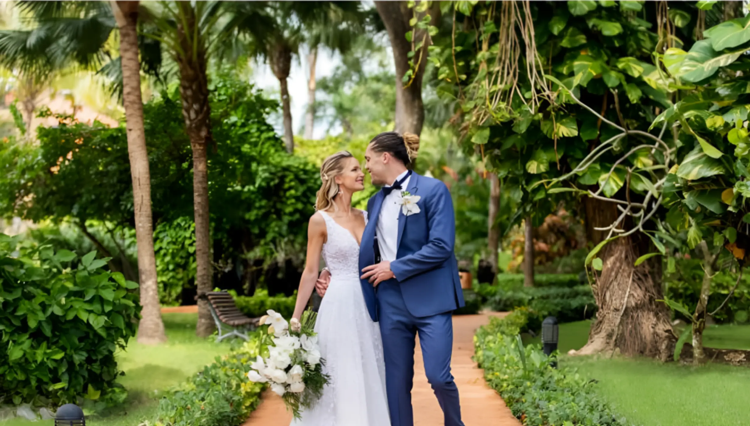 Bride and groom standing on a tropical garden path at Iberostar Selection Hacienda Dominicus, La Romana