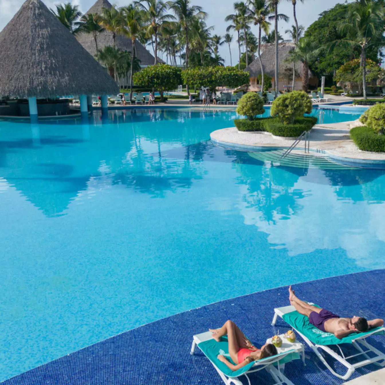 Couple lounging on chairs by the large swimming pool at Iberostar Selection Hacienda Dominicus, La Romana