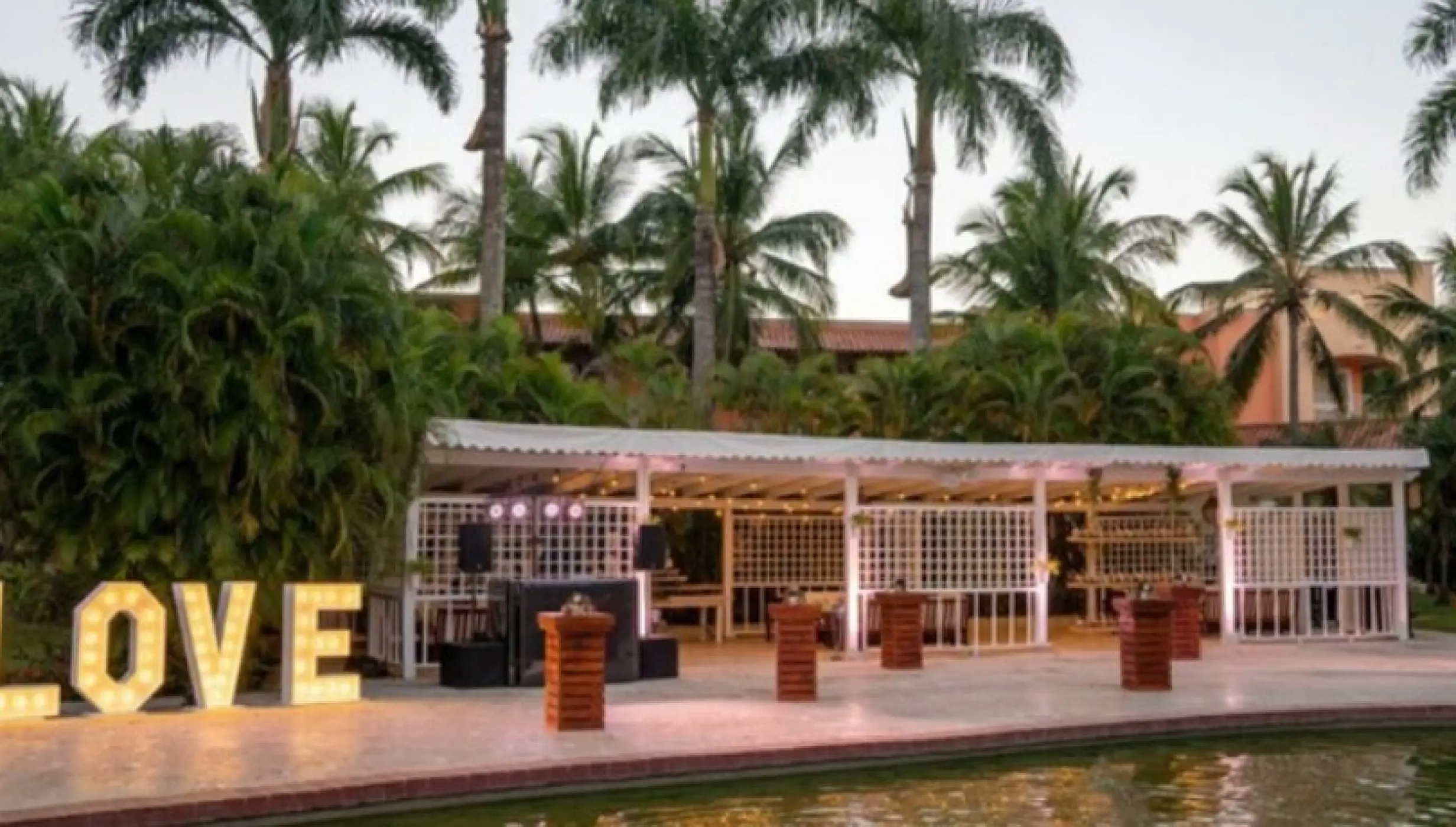 Outdoor wedding reception under a pergola with illuminated LOVE letters at Iberostar Selection Hacienda Dominicus, La Romana
