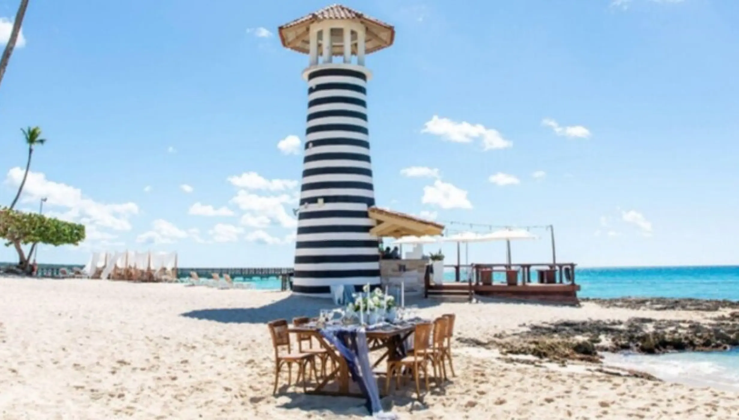 Beachfront wedding reception table by the lighthouse at Iberostar Selection Hacienda Dominicus, La Romana