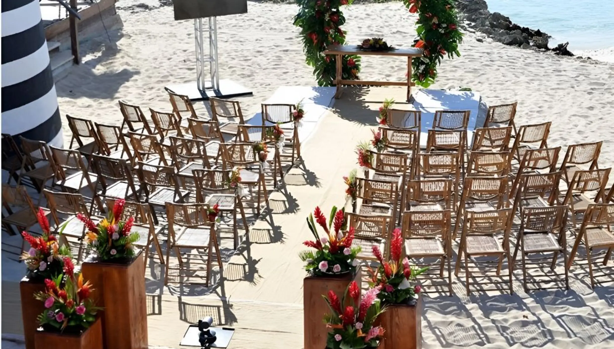 Beach wedding ceremony with a floral arch and wooden chairs at Iberostar Selection Hacienda Dominicus, La Romana