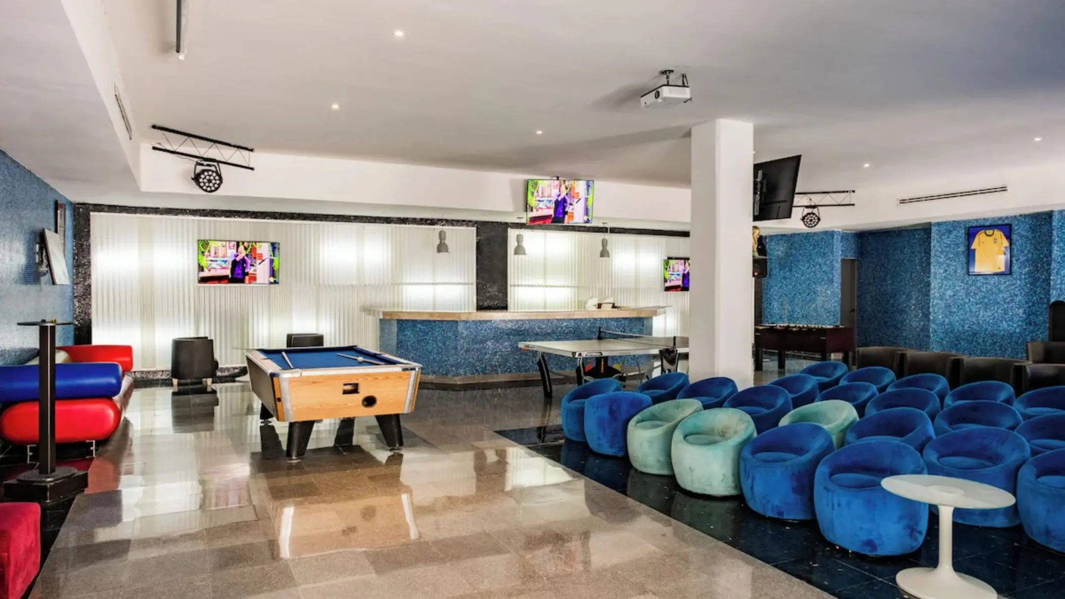 Game room with a pool table, ping pong table, and blue seating at Iberostar Selection Riviera Cancun