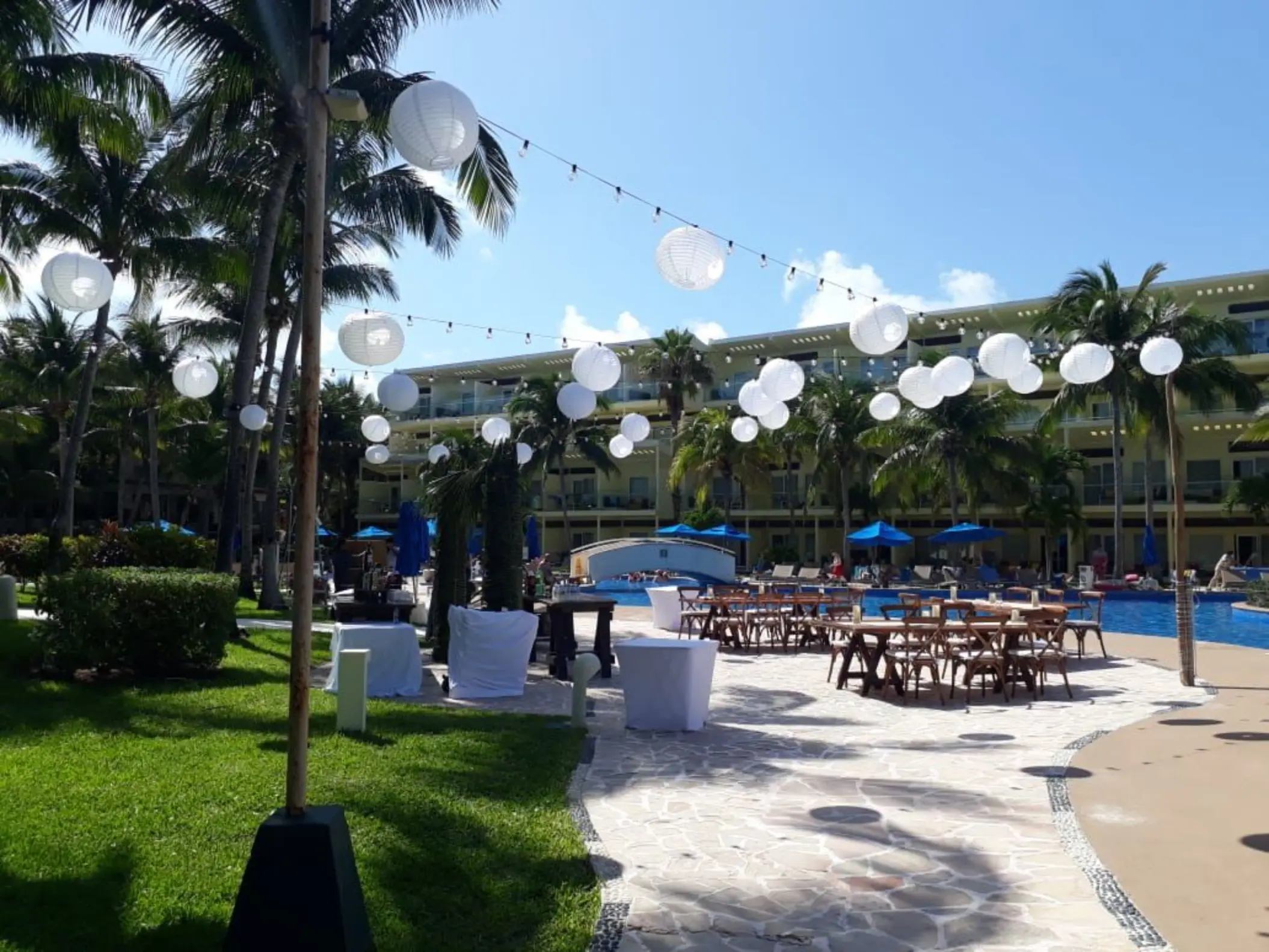 Poolside wedding reception setup with white lanterns and wooden tables at Iberostar Selection Riviera Cancun